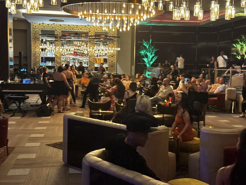 The packed Casbar Lounge during a dueling piano show, with chandeliers and palm lights